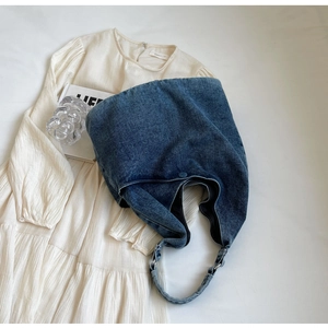 Deep blue denim hobo bag with adjustable strap and metal buckle on white fabric