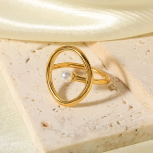 Elegant 18k gold stainless steel ring with white pearl on a travertine stone base