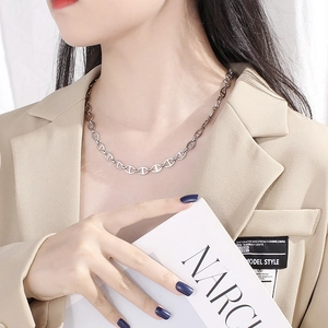 Detail of silver pig nose chain link necklace worn by model in a minimalist style
