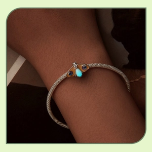 Close-up of S925 silver butterfly charm with glowing stone and blue crystals on a mesh bracelet