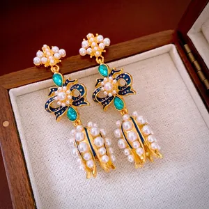 Vintage bow earrings with pearls and emerald green gemstones in a wooden box
