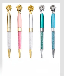 Close-up of luxury metal pens with creative crown tops and sparkling crystal fillings
