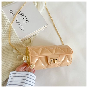 Detail of beige quilted cylinder bag with gold chain and pearl accent on white background