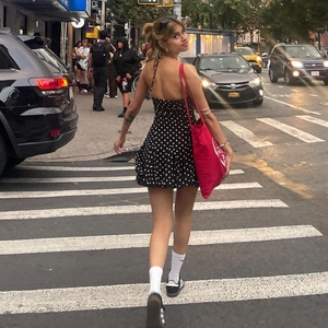 Detail of a chic black polka dot halter dress featuring backless design on street background
