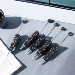 Detailed view of 5 black rhinestone beaded pens with silver metal tips on a desk