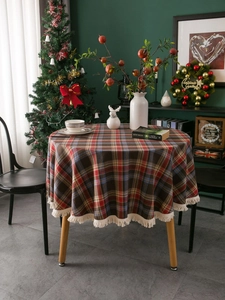 Close-up of a plaid round tablecloth with beige fringe in a festive Christmas room setting
