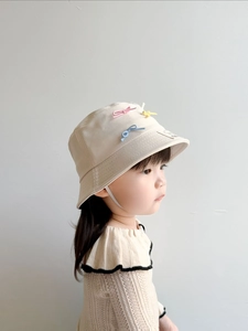 Detail of beige children's sun hat featuring colorful bows and adjustable chin strap