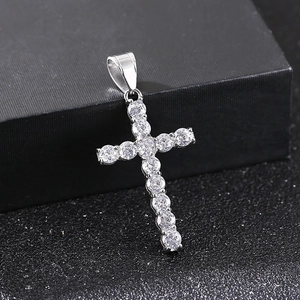 Macro del ciondolo a croce in argento scintillante con zirconi su sfondo nero strutturato