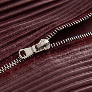Close-up of textured burgundy leather fabric and silver metal zipper detail on jacket