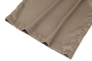 Detail shot of tan satin wide-leg pants showing premium silk texture and fine stitching