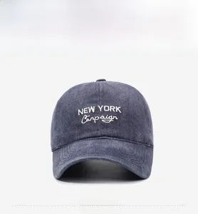 Detail of washed dark grey baseball cap featuring cream New York embroidery and vintage texture