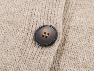 Detailed close-up of ribbed texture and high-quality resin button on beige knit cardigan