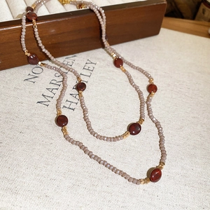 Detail of beaded necklace featuring pink faceted beads, red stones, and golden metal accents