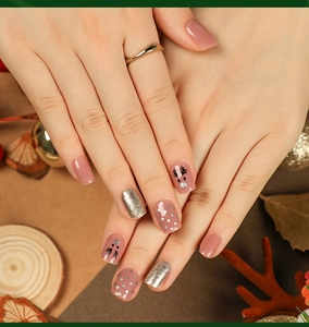 Close-up of Christmas press-on nails featuring reindeer patterns and gold glitter accents