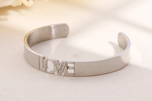 Macro shot of silver LOVE hollow bangle with sparkling rhinestone detail and metal luster