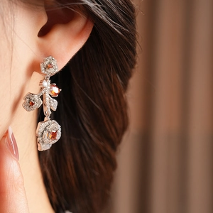 Close-up of vintage rose earring with orange zircon and diamonds on model ear