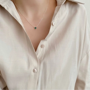 Close-up of a 925 sterling silver necklace with a small green heart-shaped zircon pendant