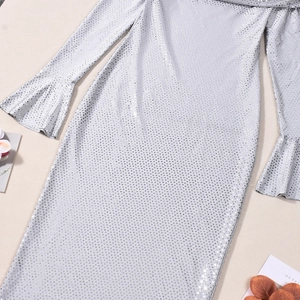 Détail du tissu à paillettes argentées et des manches évasées sur une robe à manches longues