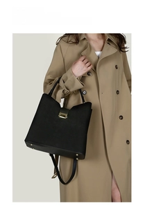 Detail of oil wax cowhide texture and gold buckle on a black shoulder tote bag