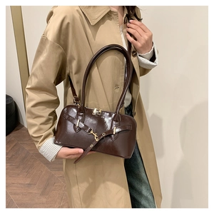 Brown patent leather bowling bag with metallic hardware details carried by a model