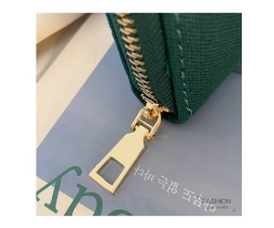 Detailed macro view of high-quality golden metal zipper on a dark green fabric clutch bag
