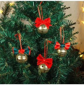 Detailed view of four golden star-cutout Christmas bells hanging on a lush green tree