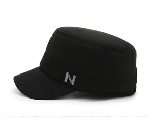 Close-up of a black flat-top winter military cap with metallic silver N-shaped badge