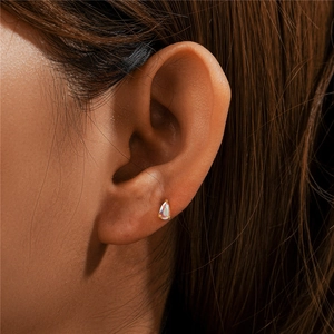 Macro shot of 925 silver gold-plated pear-shaped moonstone stud earring on model ear