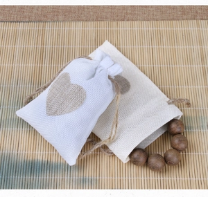 Linen drawstring jewelry pouches with heart pattern on bamboo mat with wooden beads