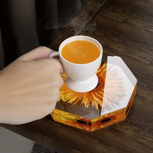 Hexagonal clear resin coaster with sunflower design on a rustic wooden table