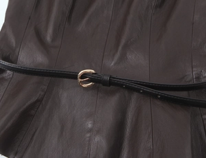 Dettaglio in pelle marrone scuro con una sottile cintura nera e fibbia rotonda dorata