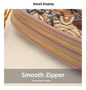 Detail of smooth gold zippers and pink leather piping on a woven jacquard shoulder bag