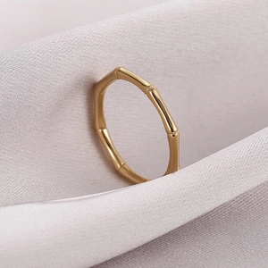 Polished golden stainless steel bamboo joint ring on soft grey silk fabric texture