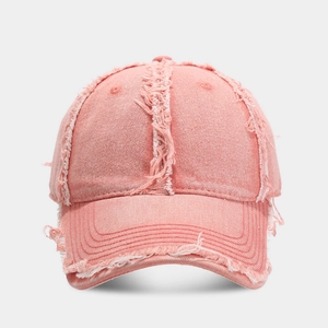 Detailed view of pink distressed denim baseball cap with raw frayed edges and retro texture