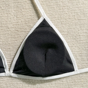 Detail of black bikini top with white contrast piping and high-quality stitching texture