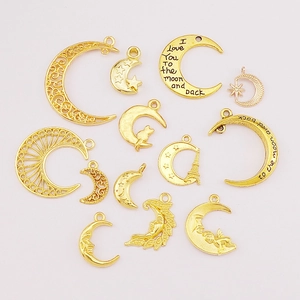 Flat lay of thirteen assorted golden crescent moon alloy charms with star and cat details