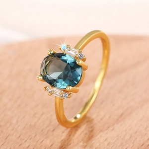 Elegant gold oval ring with dark blue gemstone and sparkling accent diamonds