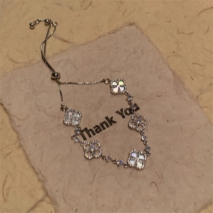 Detail of clover bracelet with white shell inlay and zircon stones on a thank you card