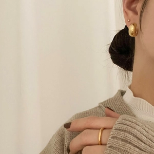 Close-up of 925 sterling silver gold-plated dome hoop earrings and minimalist ring on model