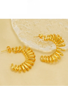 Macro view of 18k gold plated spring style C-shape hoop earrings on silk background