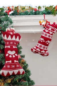 Detail of red and white knit bone-shaped Christmas stocking with paw patterns on a tree