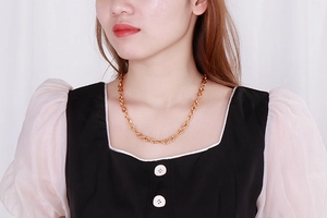 Elegante collana dorata a maglie infinito indossata da una modella sul collo