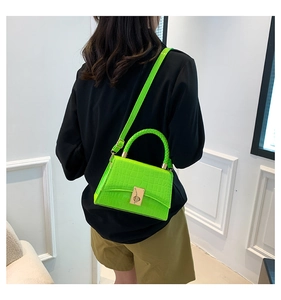 Detail of green crocodile texture handbag with woven handle and gold lock closure