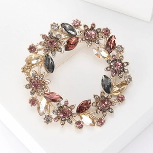 Close-up of sparkling rhinestone flower wreath brooch with pink and champagne crystals