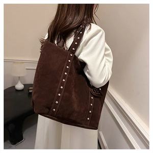 Detail view of dark brown faux suede tote bag featuring silver studs and a small side pocket