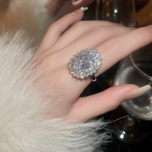 Detail of an oval cubic zirconia ring on finger holding a glass with elegant fur trim