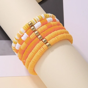 Detail of bohemian layered beaded bracelets with orange polymer clay heishi beads