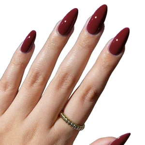 Glossy burgundy almond-shaped press-on nails on hands with a golden ribbed ring