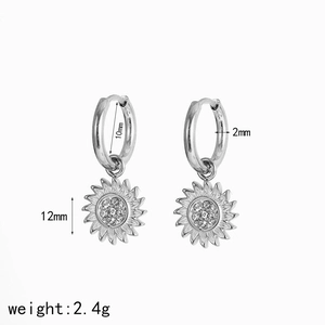 Macro detail of silver sunflower earrings with sparkling cubic zirconia on white background
