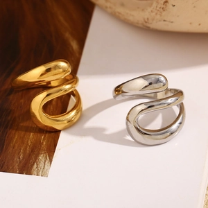 Macro shot of 18K gold and silver plated triple layer teardrop rings on wood surface